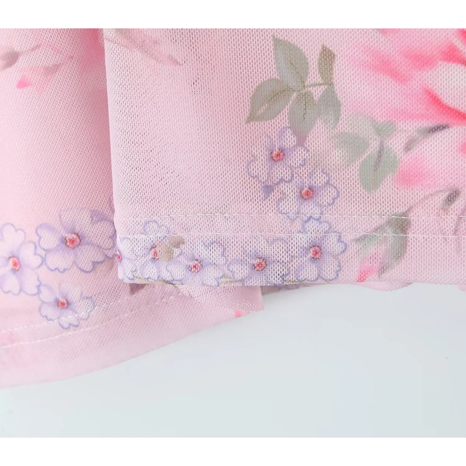 Close‑up finished hem stitching of pink floral mesh mini dress, delicate flower pattern on mesh overlay