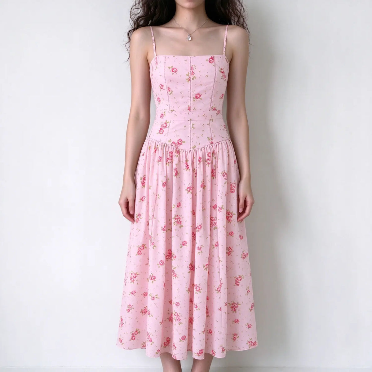 Model wearing pink floral square neck spaghetti strap maxi dress, fitted corset waist, flowy gathered long skirt, plain white background