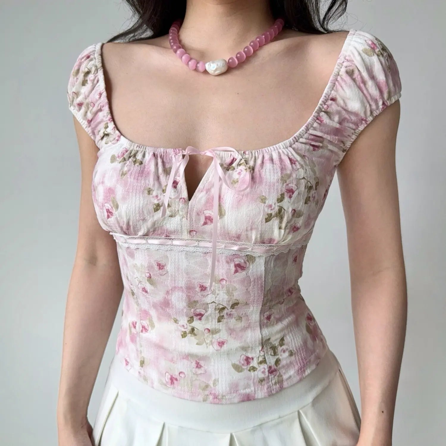Close-up shot of the pink floral square-neck top, highlighting the corset-style lace trim and ribbon tie