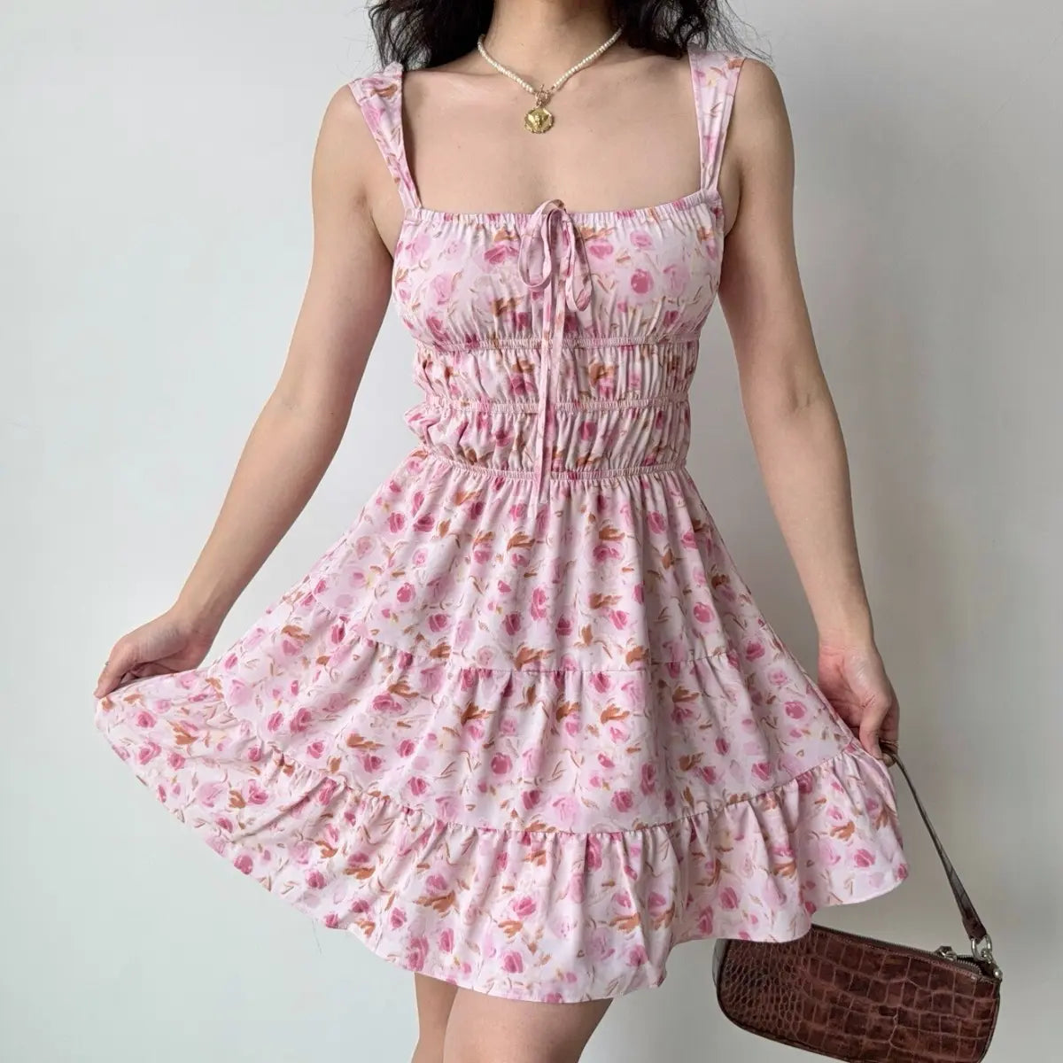  The pink floral dress paired with a pearl necklace, highlighting the square neckline.