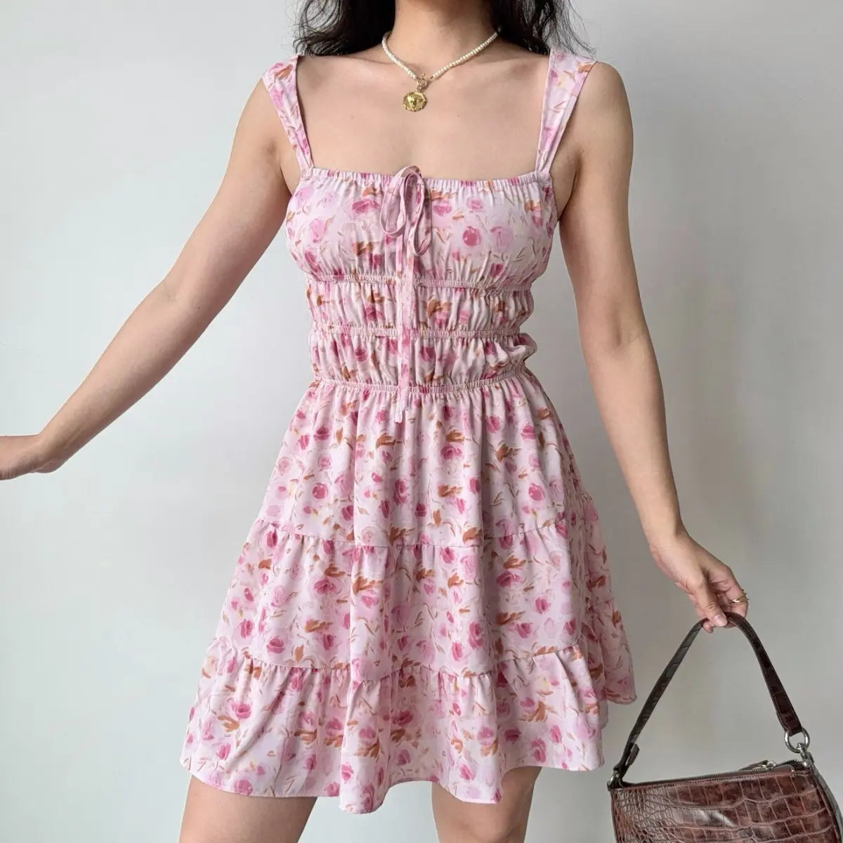 Slight angle view of the pink floral tiered dress, showing the flowy ruffled hem.