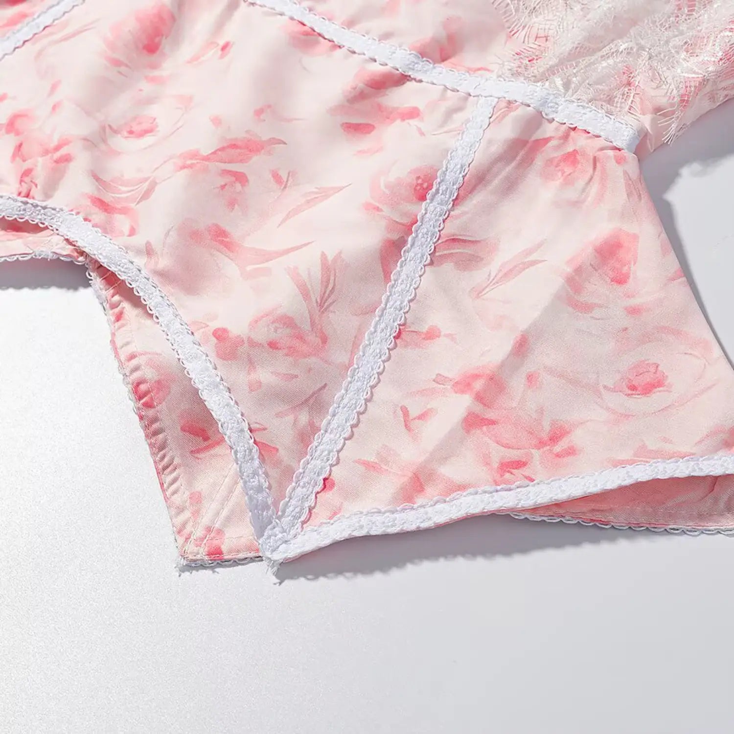 Close-up asymmetric pointed hem with white lace piping pink floral blouse