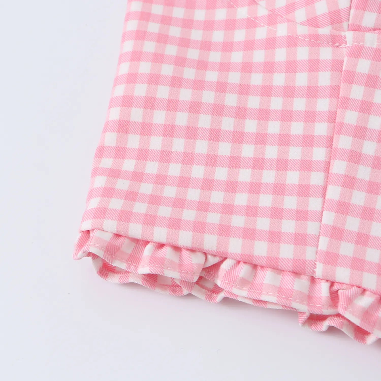 Close-up of the ruffled hem edge on the pink gingham corset crop top