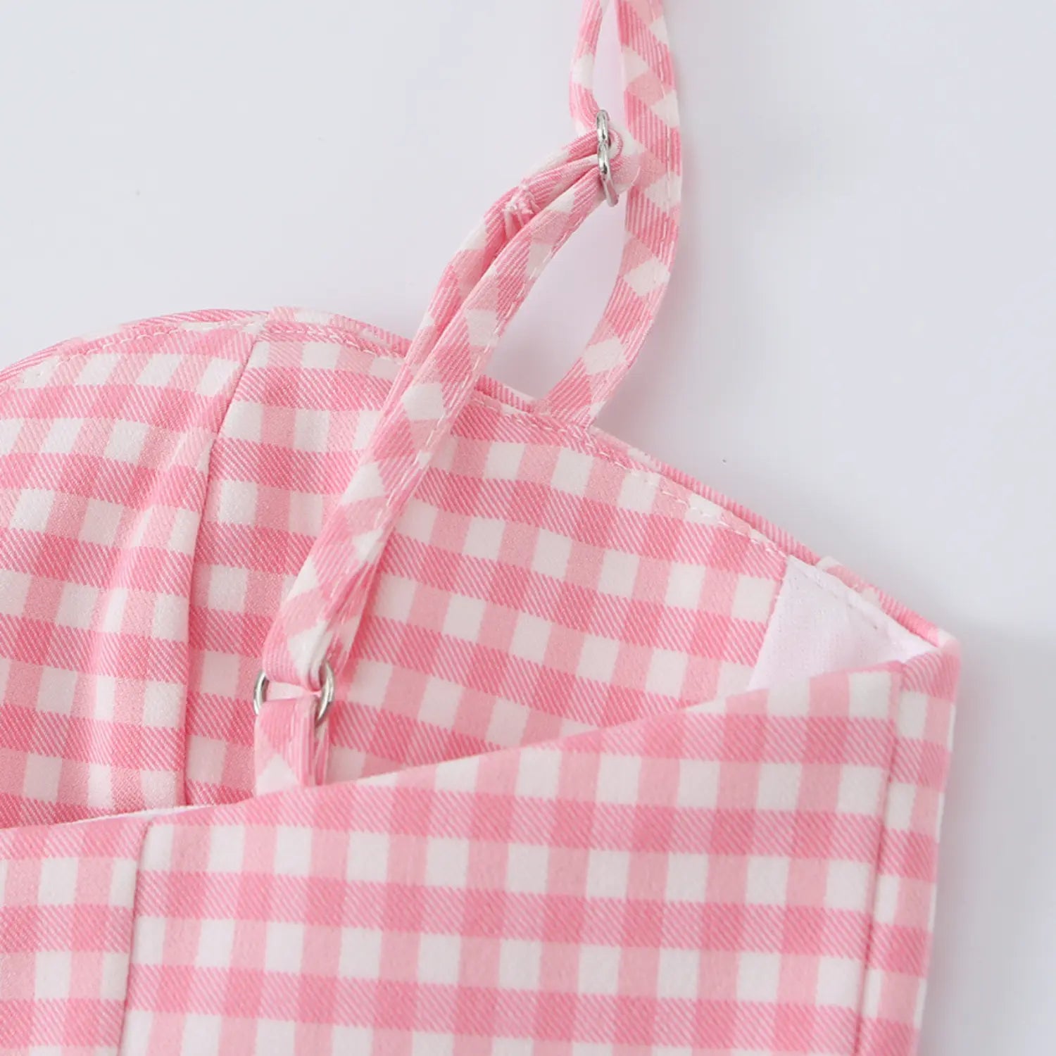 Close-up of the adjustable metal ring slider on the thin pink gingham cami strap