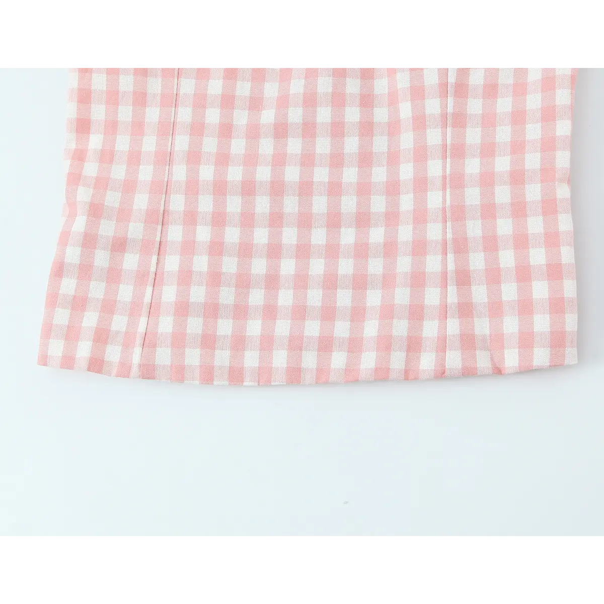 Close-up of the straight hem and vertical darts on the pink and white gingham cami top.