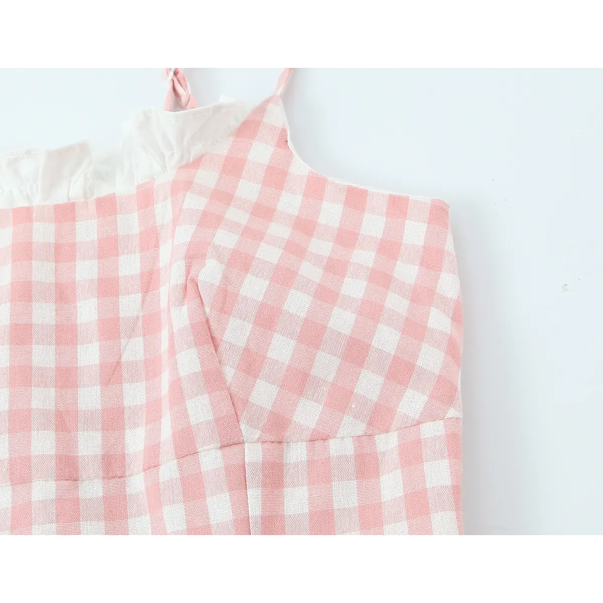 Close-up of the ruffled white trim at the square neckline and the adjustable spaghetti straps.
