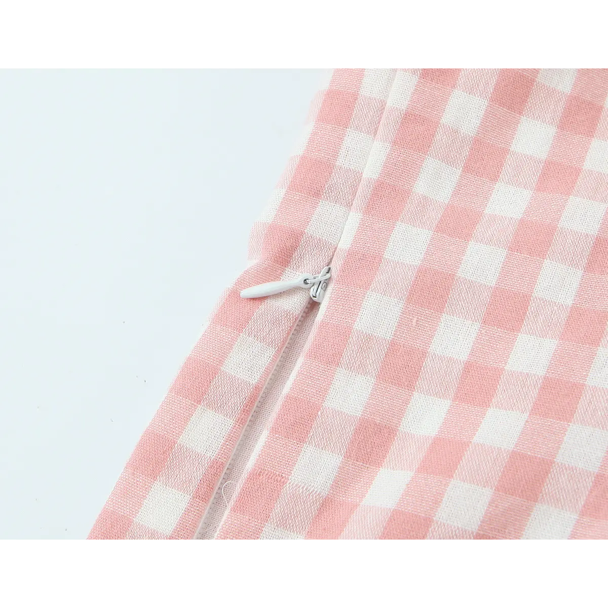 Close-up of the invisible side zipper with a white pull tab, seamlessly integrated into the gingham fabric.