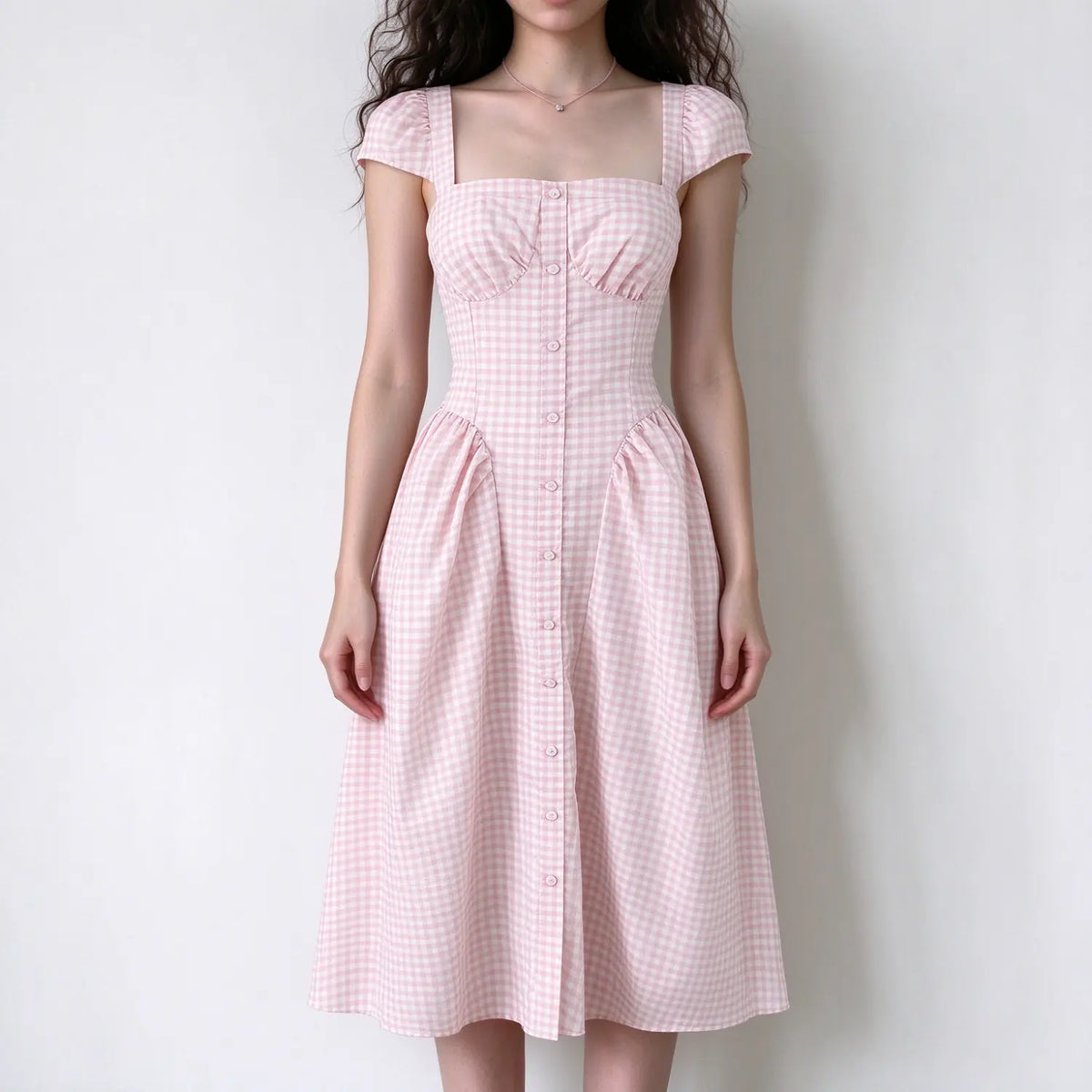 Model wearing pink gingham square neck cap sleeve maxi dress with front button details and full A-line skirt, white background