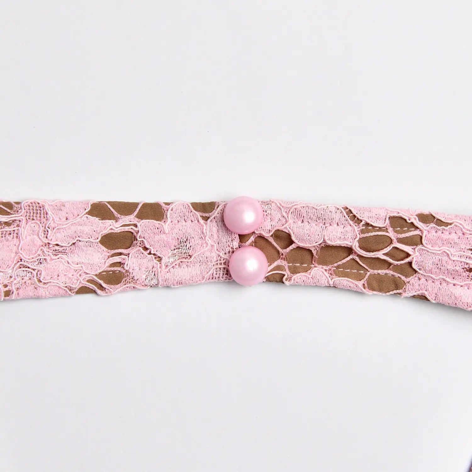 Extreme close‑up pink pearl buttons on halter neck lace strap