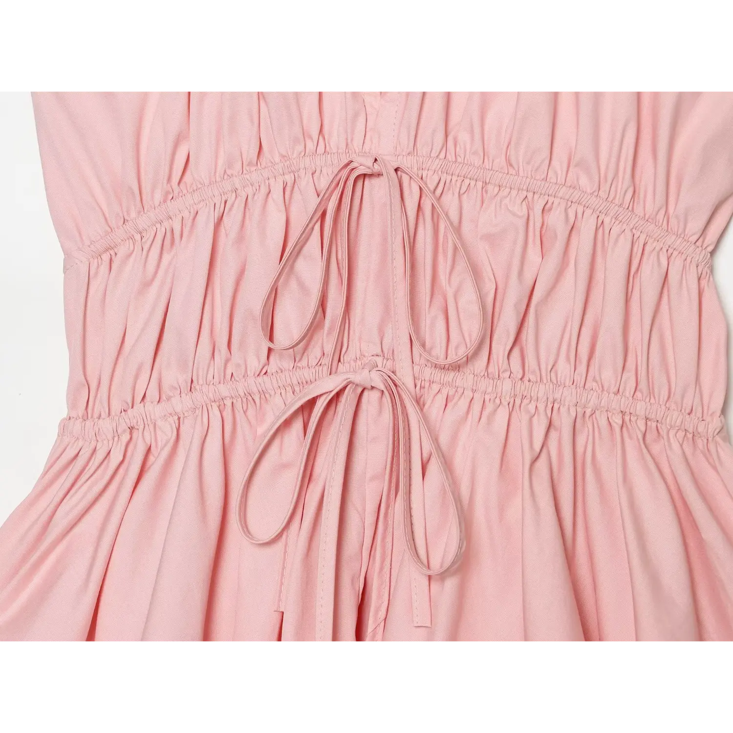 Macro close-up of dual self-fabric drawstring ties at elastic ruched waist