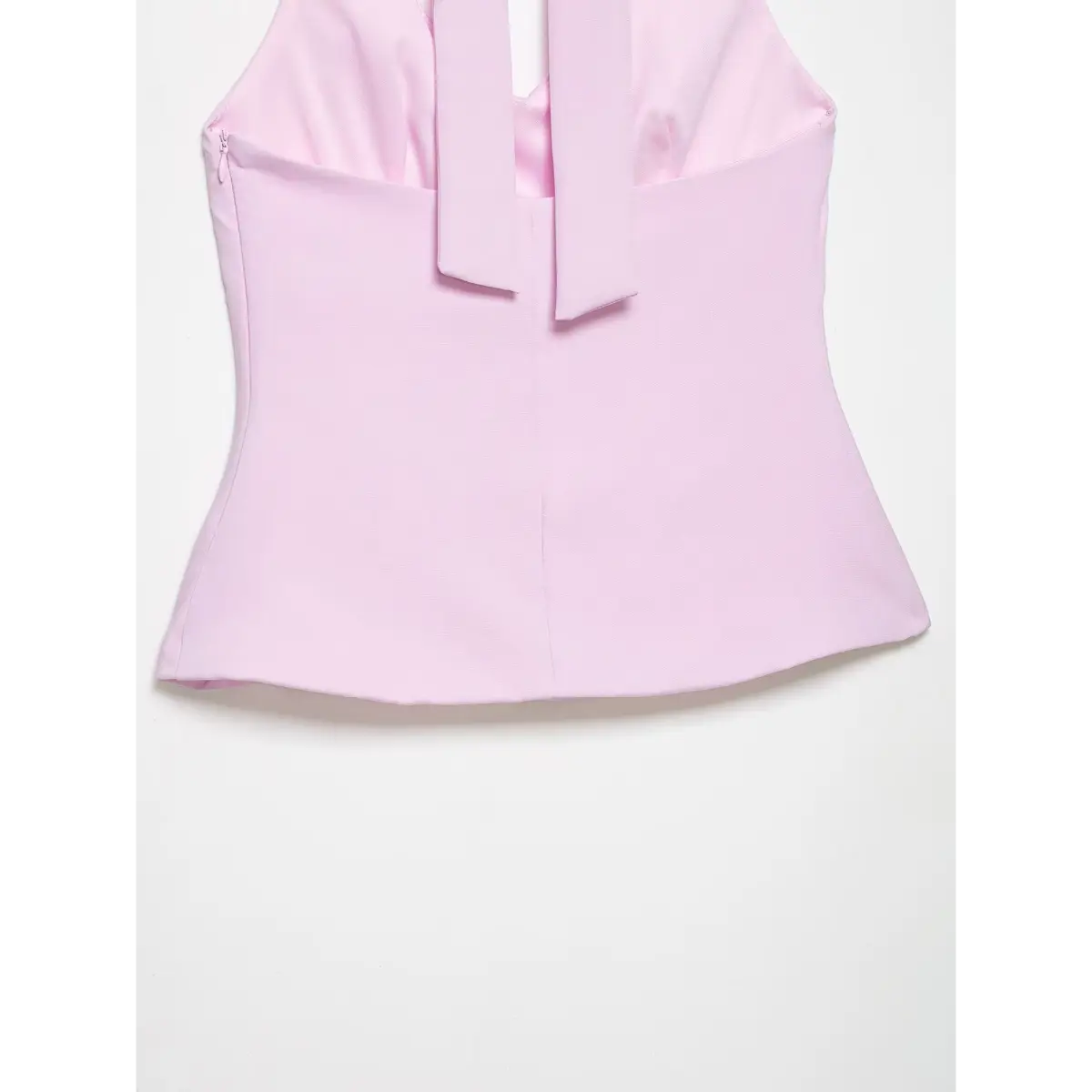 Close-up of the top's back hem, showing the zipper and structured fit.