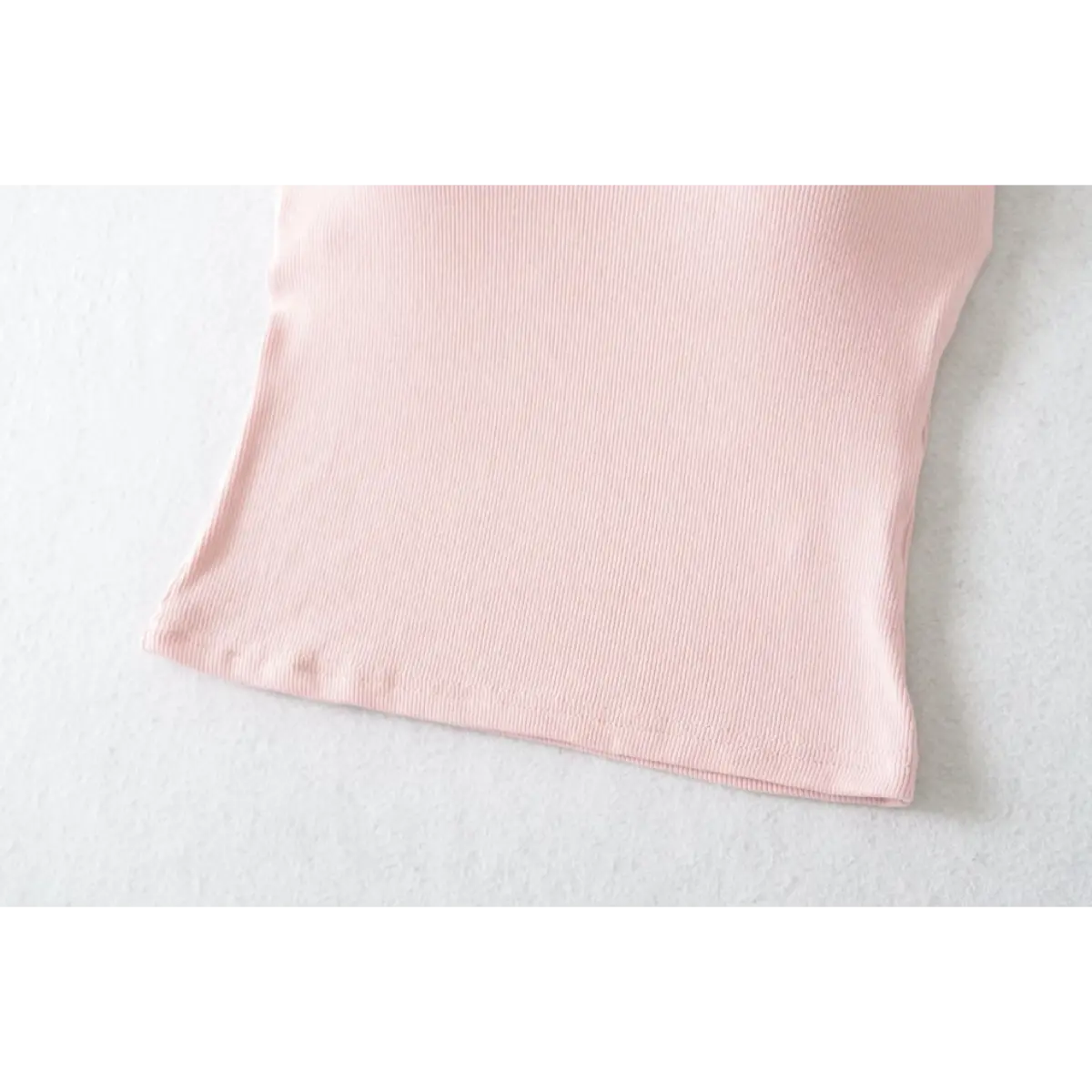 Close-up of the bottom hem on a pink ribbed halter top, showing the stitching and texture.