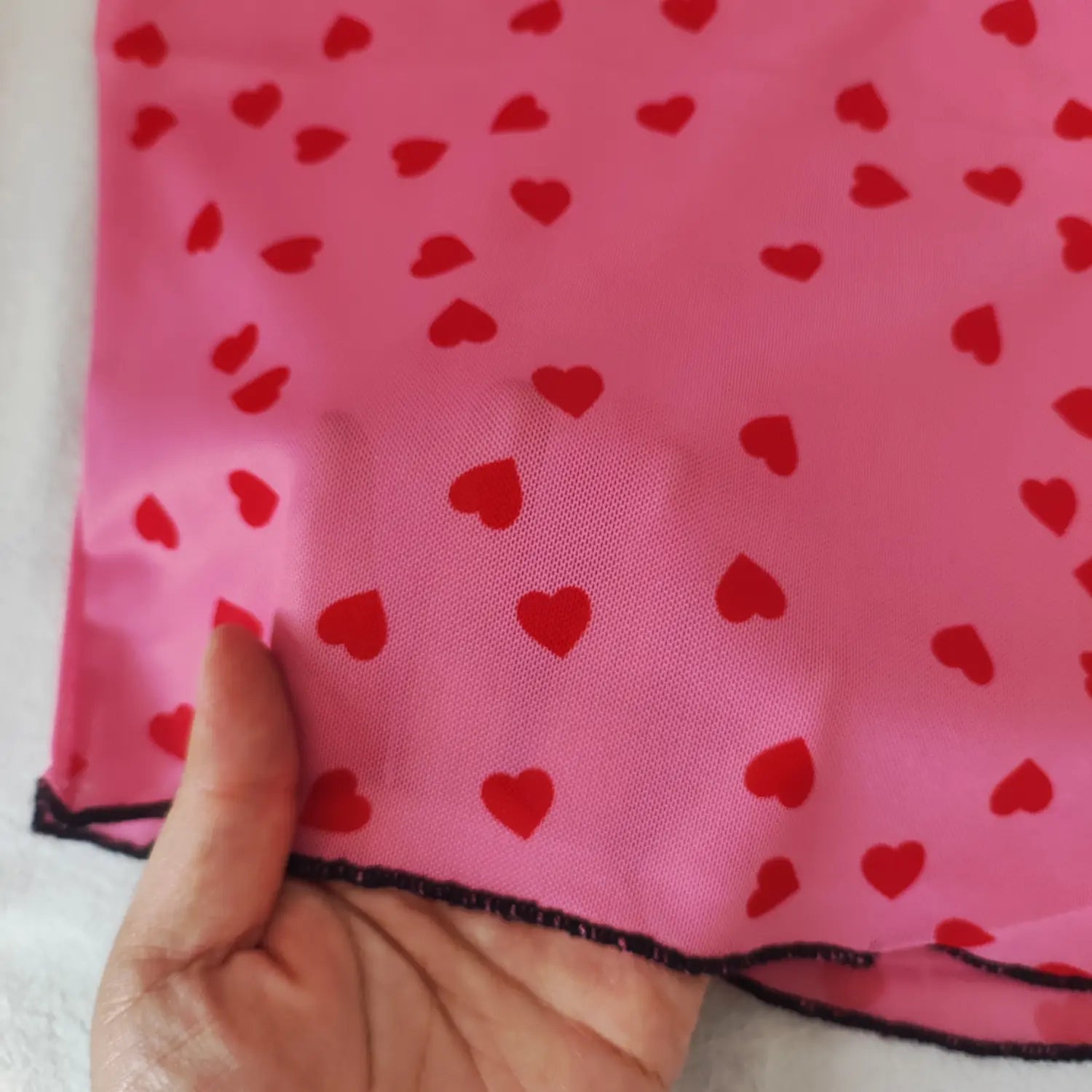Close‑up sheer mesh fabric texture and red heart print of pink short sleeve top