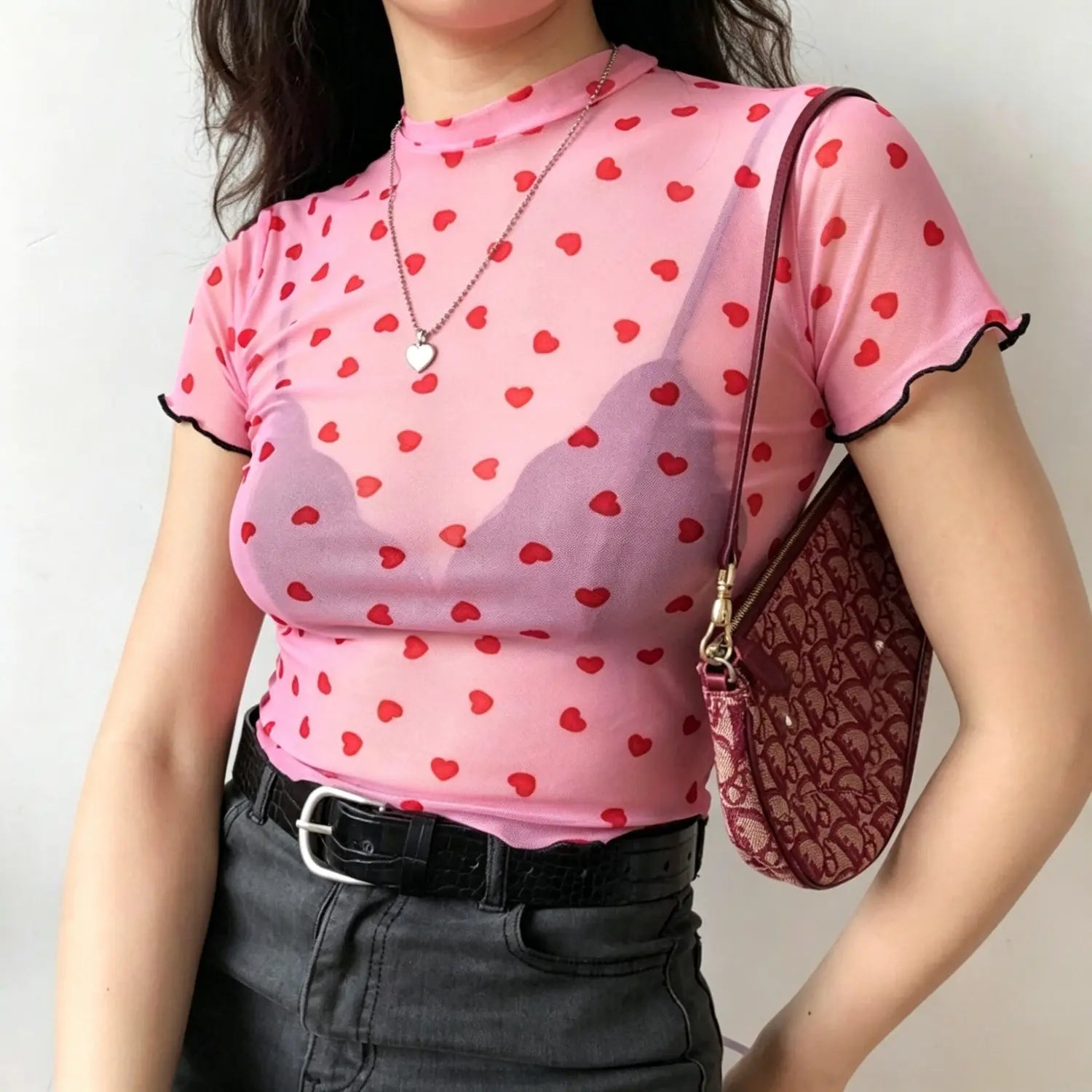 Model side torso shot pink heart print sheer mesh top with black lettuce edge sleeve cuffs