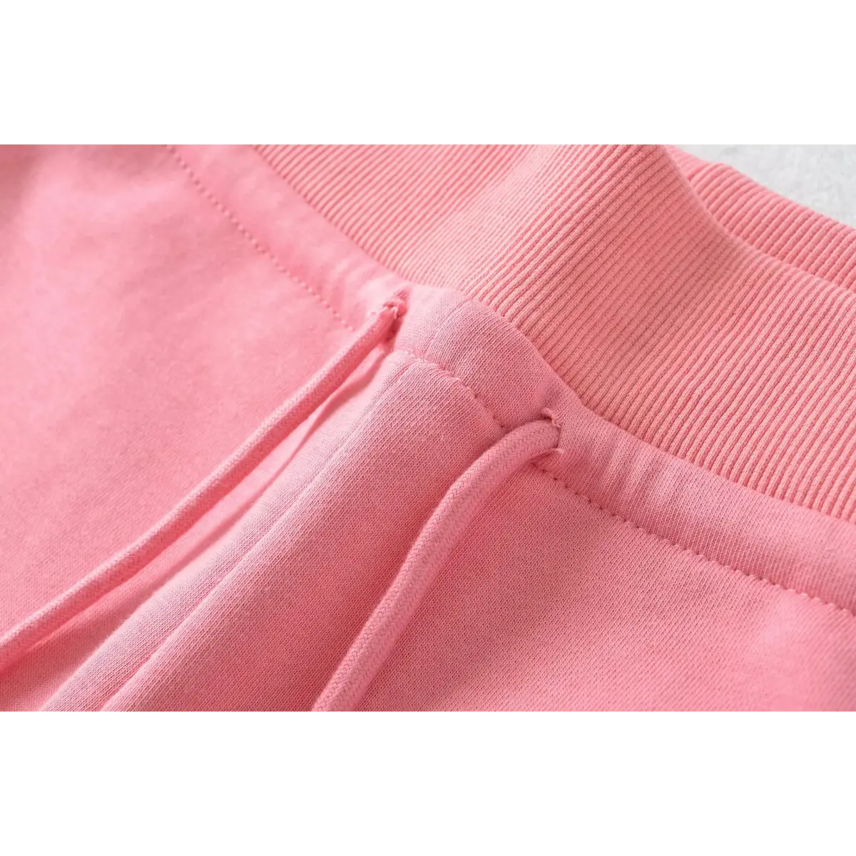 Close-up of the drawstring channel and stitching on pink high-waisted drawstring shorts.
