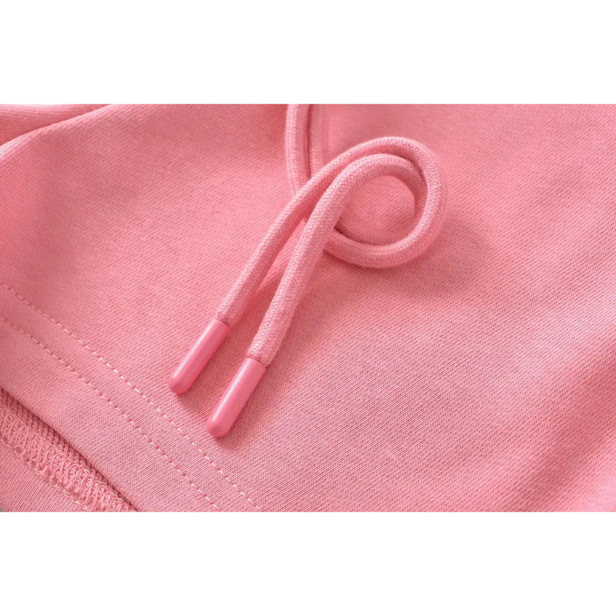 Close-up of the drawstring and plastic tip on pink high-waisted drawstring shorts.