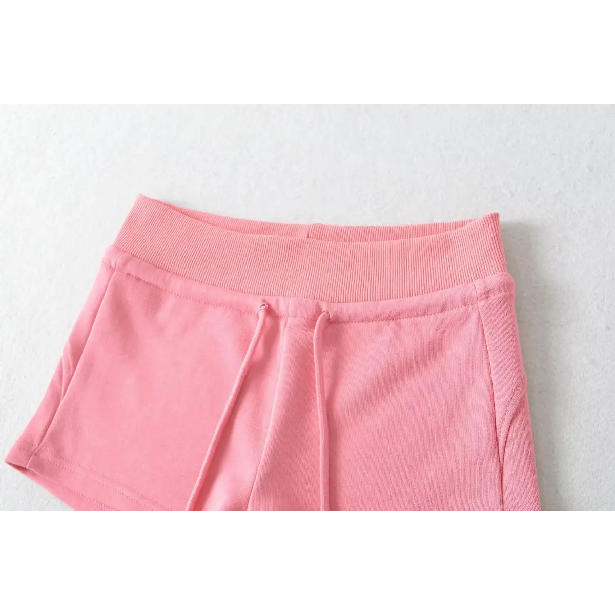 Close-up of the waistband and drawstring on pink high-waisted drawstring shorts, showing the ribbed texture.
