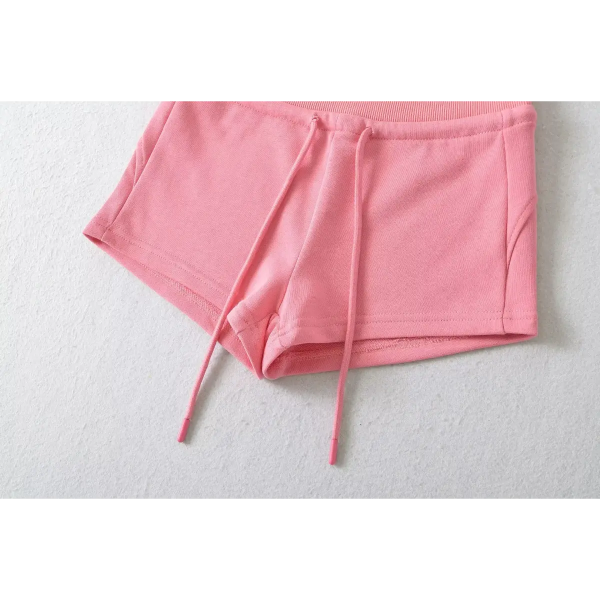 Close-up of the side hem and drawstring on pink high-waisted drawstring shorts.