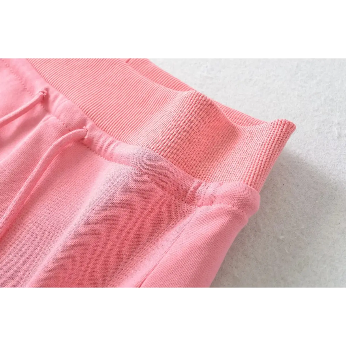 Close-up of the ribbed waistband and stitching on pink high-waisted drawstring shorts.