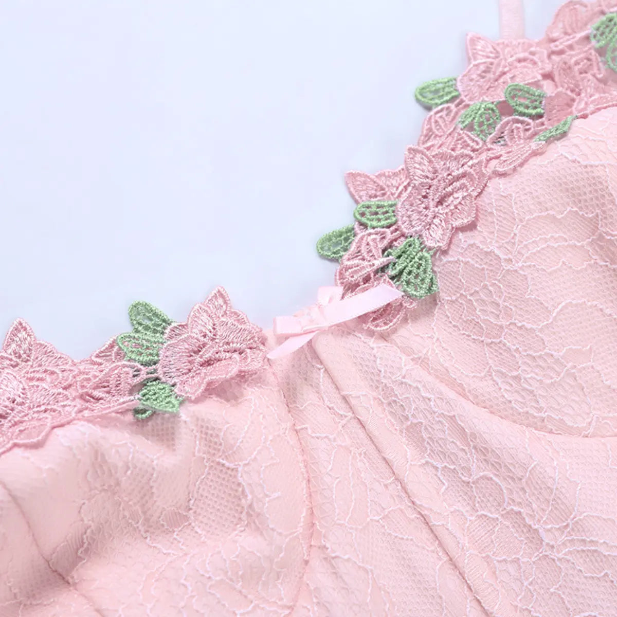 Close-up of the floral appliqu on the pink lace bustier top, showing the pink flowers, green leaves, and center bow