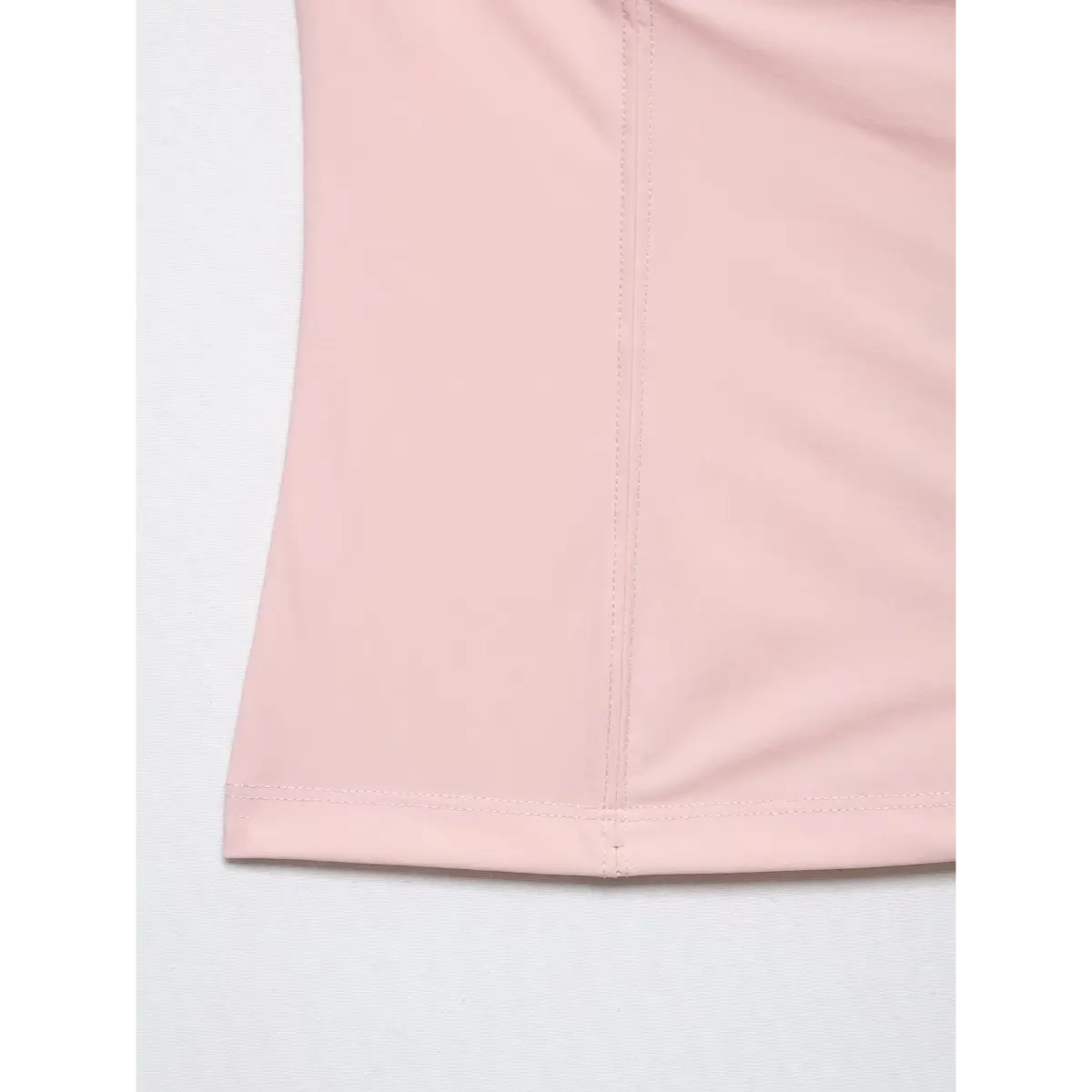 Close-up of the clean stitched hem and vertical center seam on the light pink camisole.