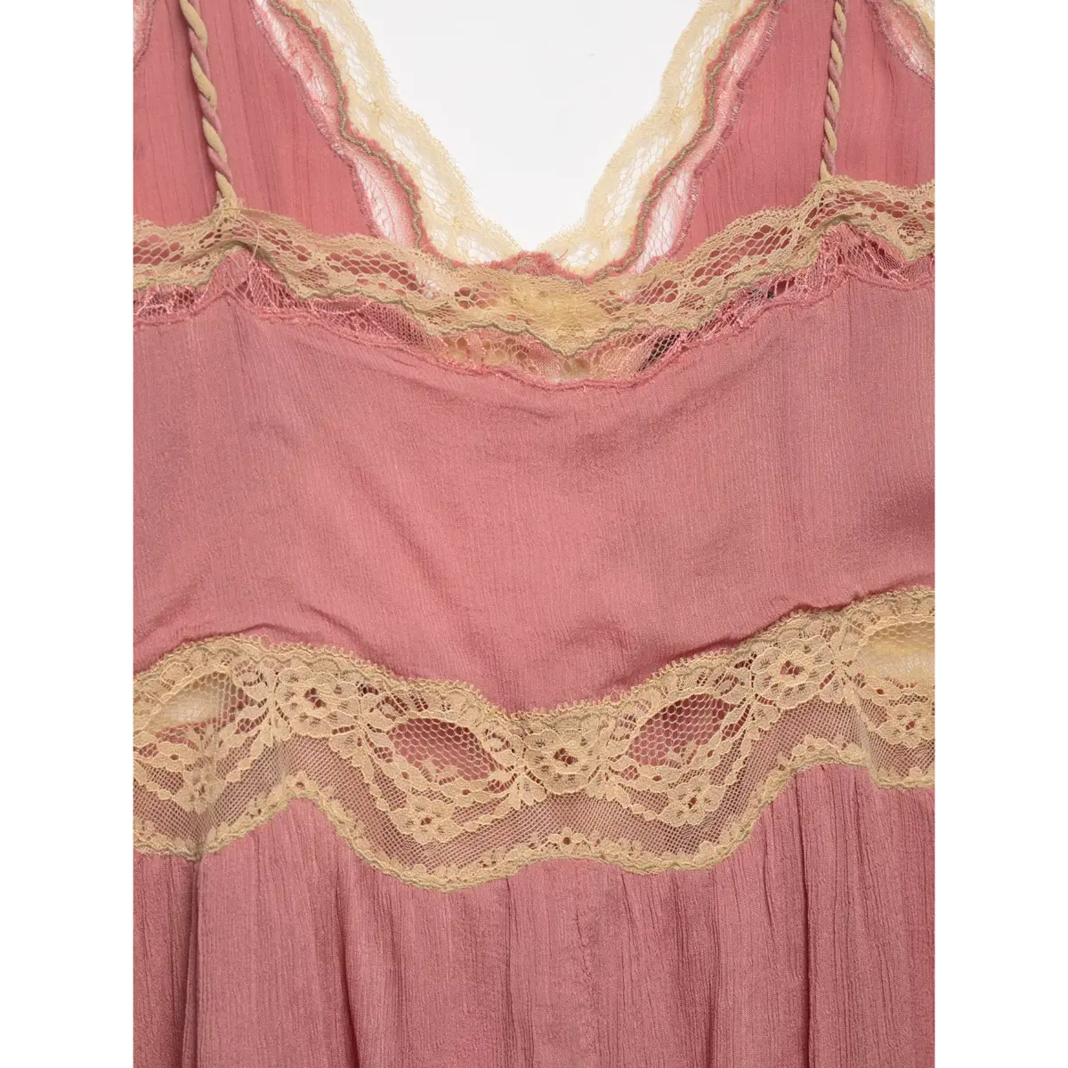 Close-up of the front torso of a pink lace-trimmed peplum cami top, showing the layered lace and gathered fabric.