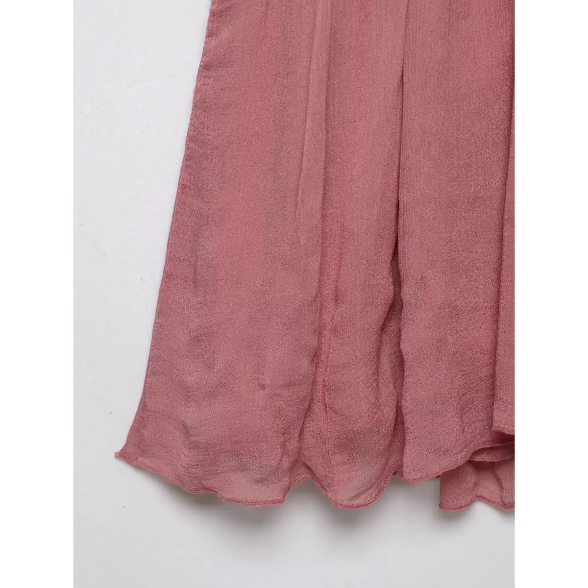 Close-up of the flowy peplum hem on a pink lace-trimmed cami top, showing the soft texture.

