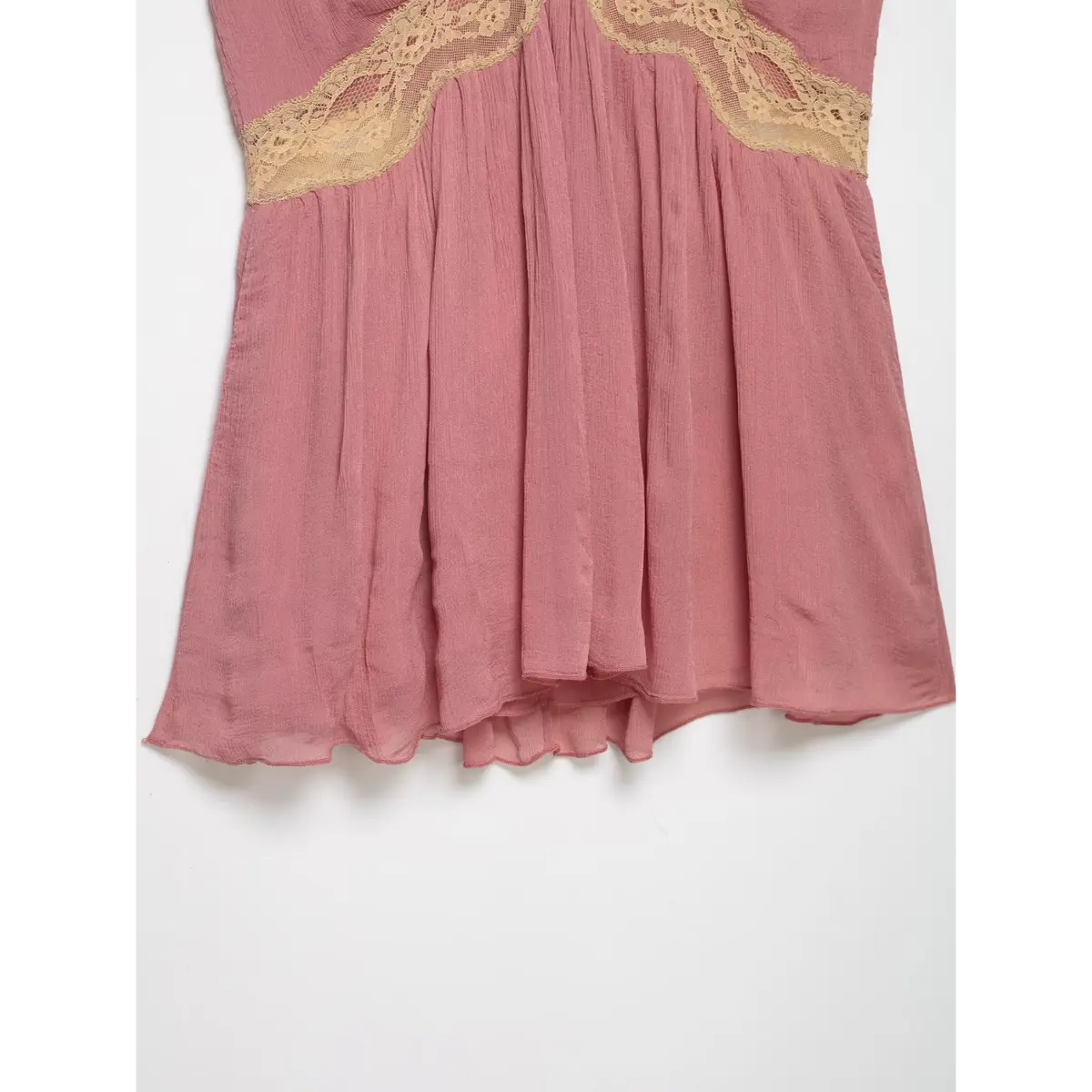 View of the peplum hem of a pink lace-trimmed cami top, focusing on the flowy silhouette.
