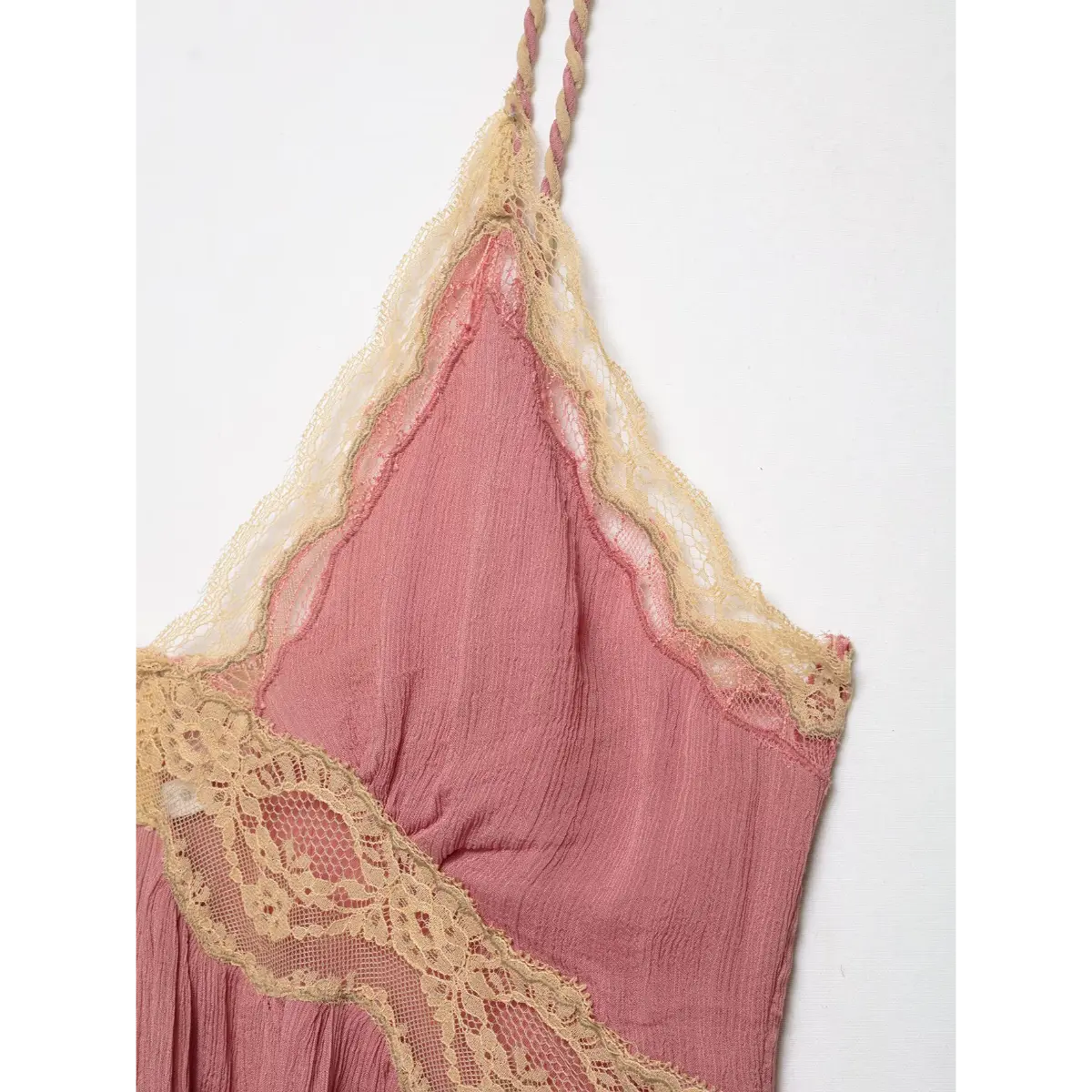 Close-up of the beige lace trim on a pink peplum cami top, highlighting the intricate pattern and layered design.
