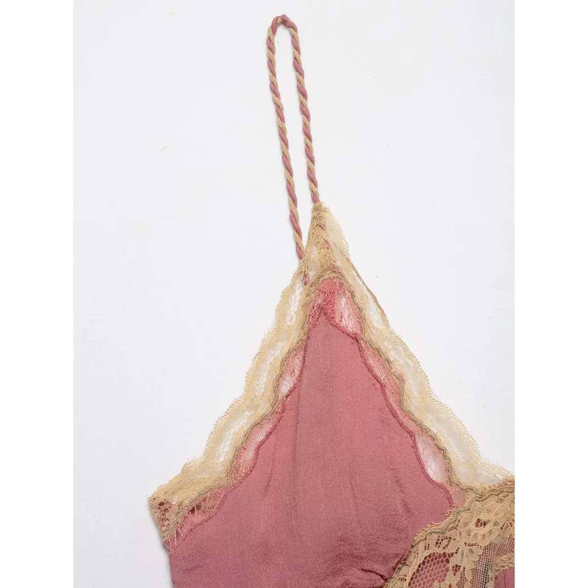 Side view of a pink lace-trimmed peplum cami top, showing the braided strap and scalloped lace trim.