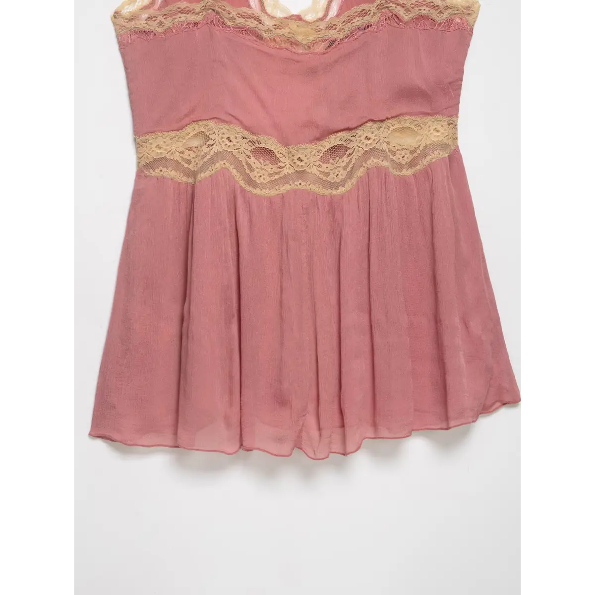 Close-up of the beige lace waist trim on a pink peplum cami top, highlighting the gathered fabric above the peplum.