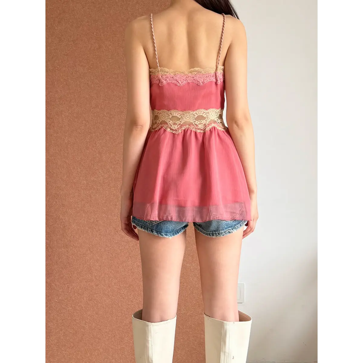 Back view of a pink lace-trimmed peplum cami top, highlighting the braided spaghetti straps and lace trim.