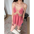 Woman styled in a pink lace-trimmed peplum cami top, paired with denim shorts and white knee-high boots.