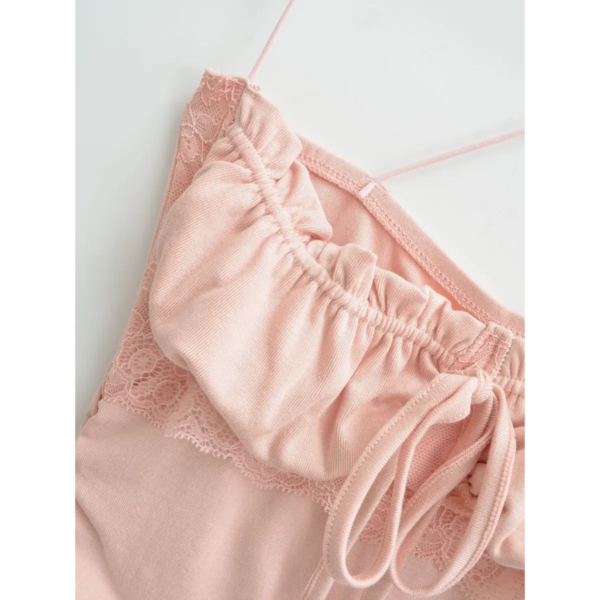  Close-up of the bust area on pink lace-trim cami top, showing gathered fabric, drawstring and lace trim.
