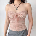 Model wearing pink lace-trim cami top with grey bottoms, showing the fitted silhouette and crisscross straps.