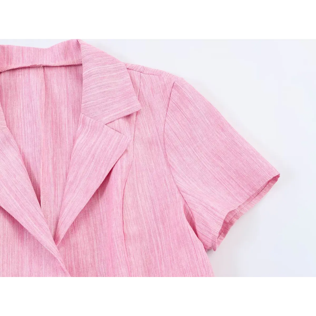 Close-up view of the notched lapel and short sleeve on a pink linen blazer dress, showing the tailored construction.