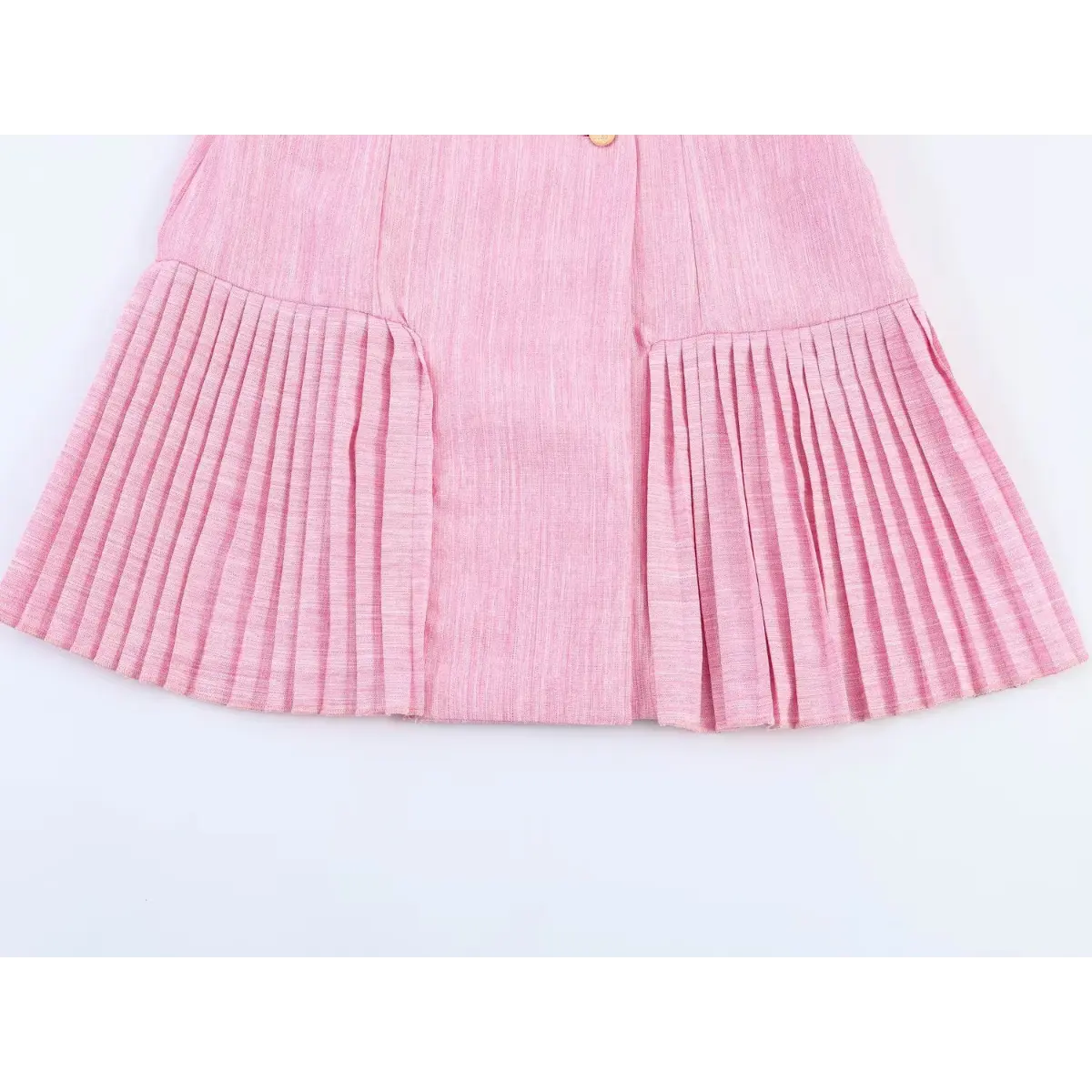 Close-up detail shot of the pleated hem on a pink linen blazer dress, showing the crisp folds and tailored finish.
