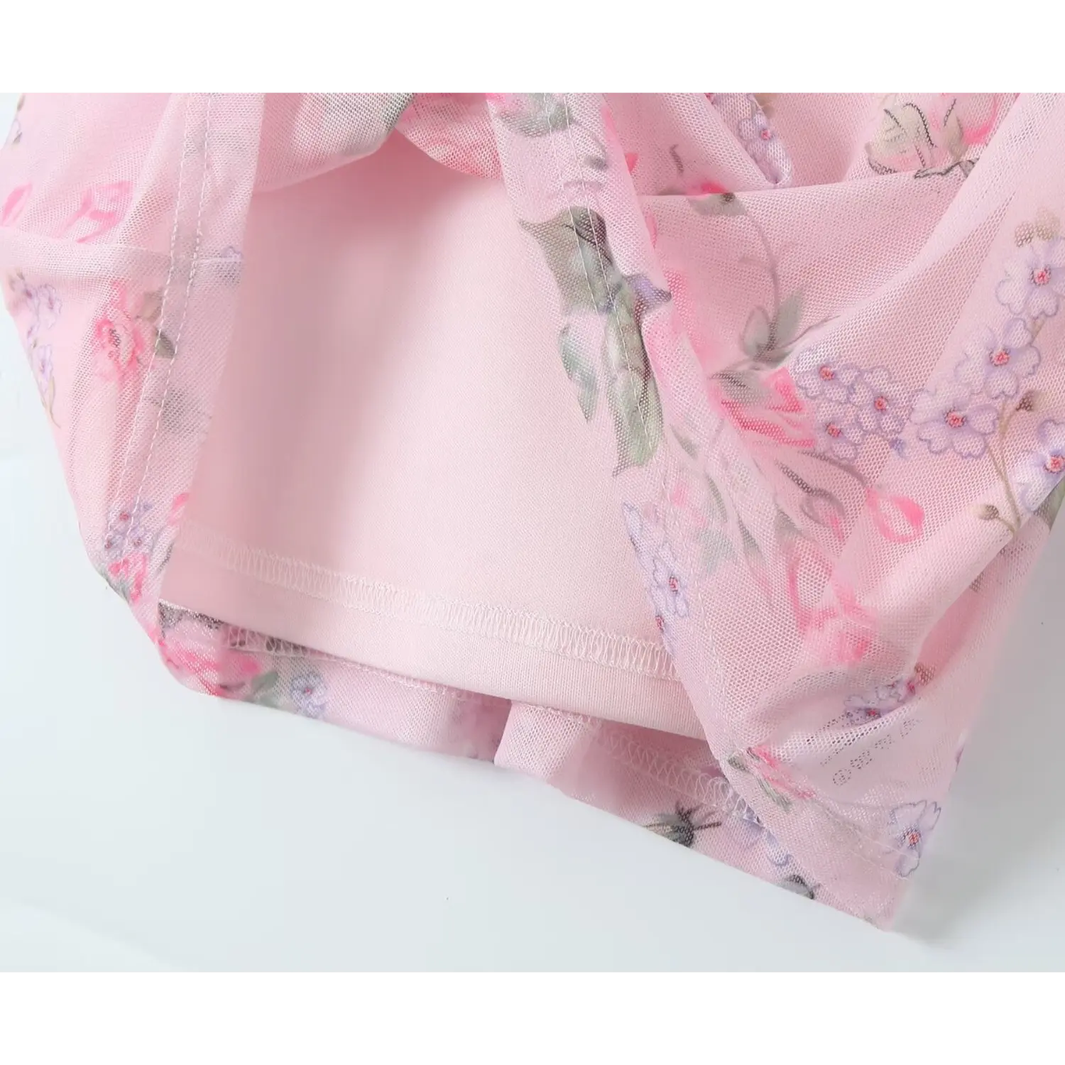 Close‑up showing outer floral mesh overlay and solid pink inner lining of cami mini dress