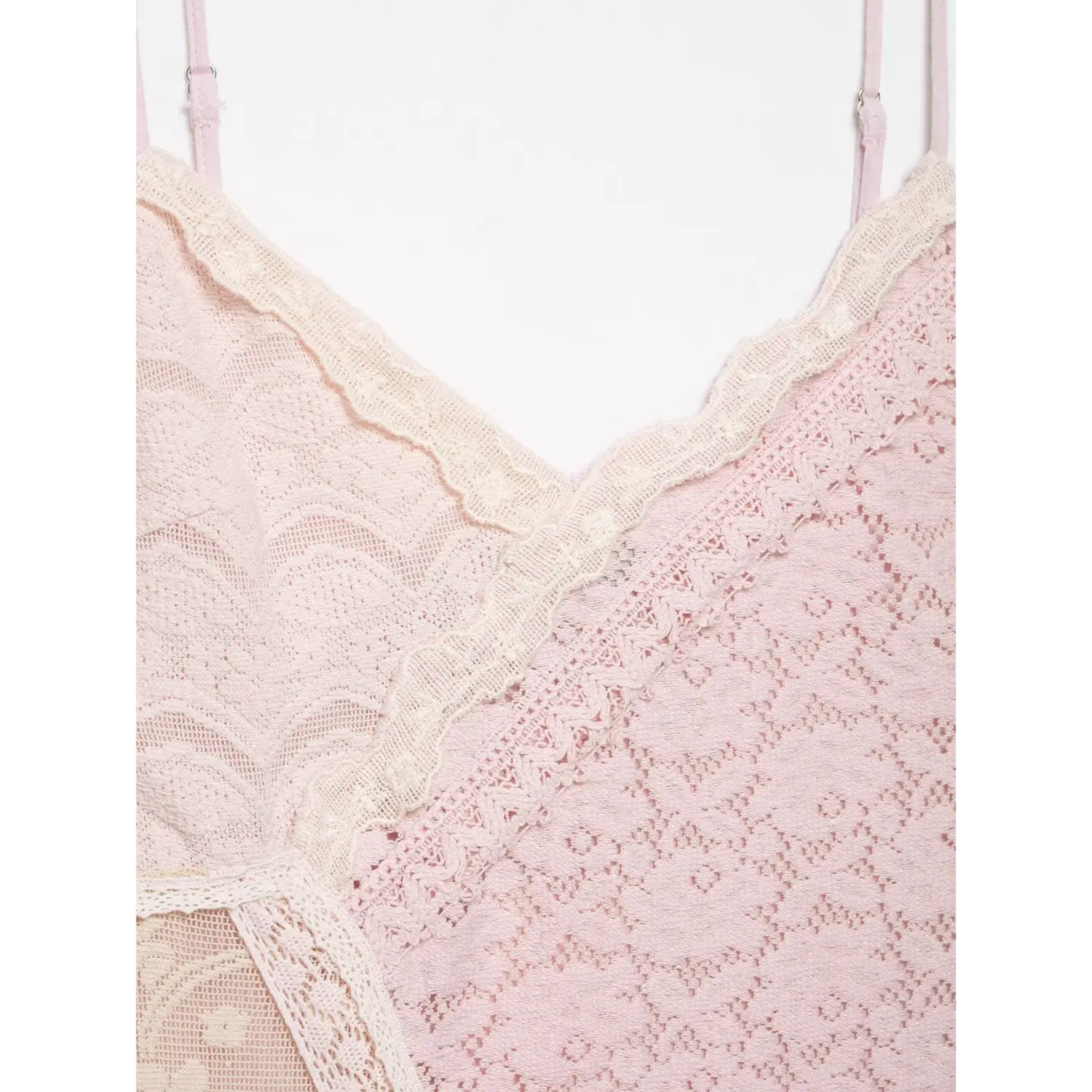 Extreme close-up isolated white background, diagonal mixed pattern contrast lace panel and scalloped v neck lace trim of pink lace cami dress