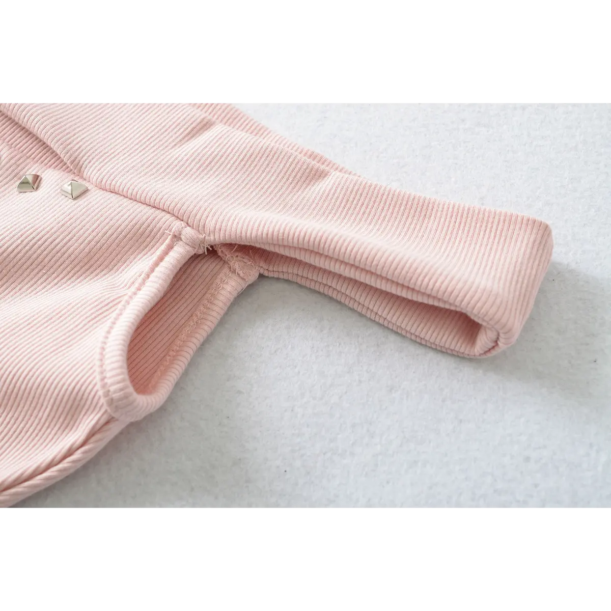 Close-up of the folded neckline and seam details on a pink ribbed off-shoulder dress.