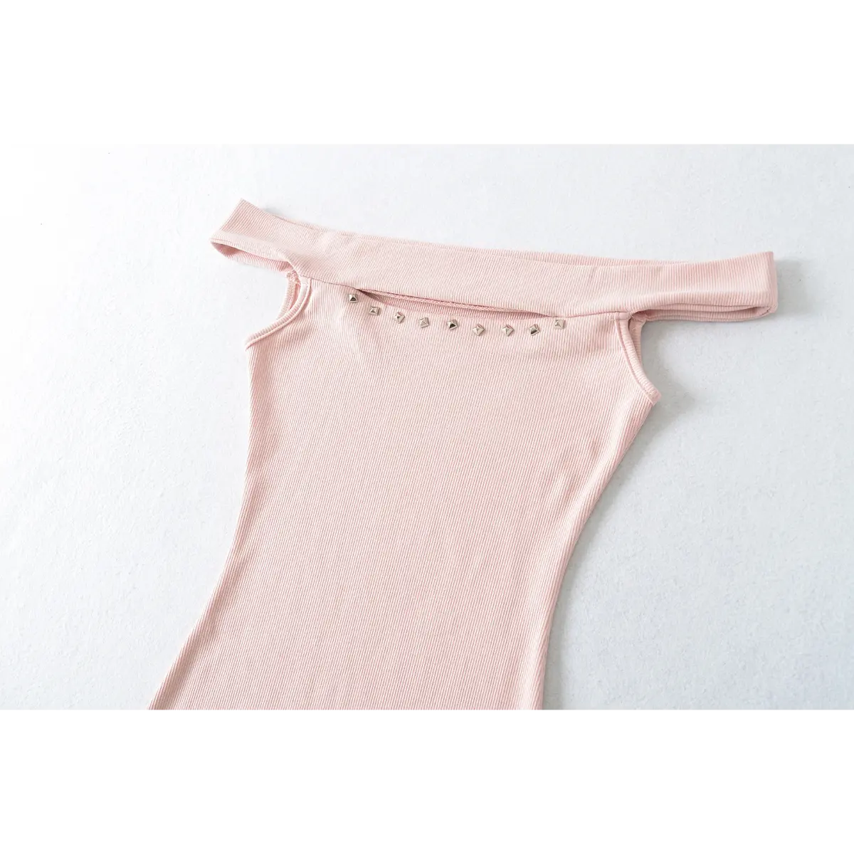 Front view detail of a pink ribbed off-shoulder dress, showing the neckline and stud accents.