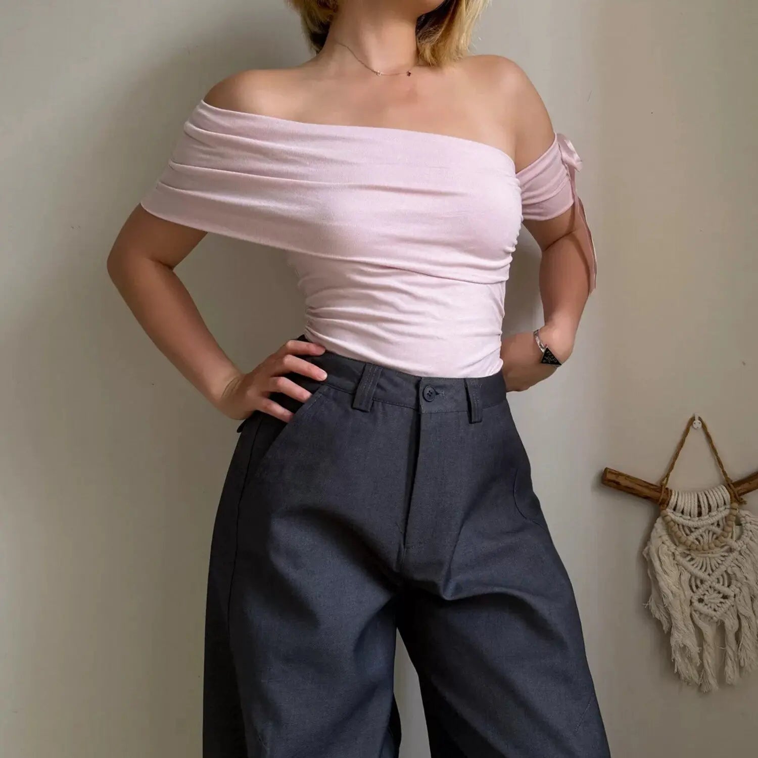 Pink off shoulder ruched crop top with bow sleeve paired with charcoal gray high waist wide leg pants, front view women casual outfit