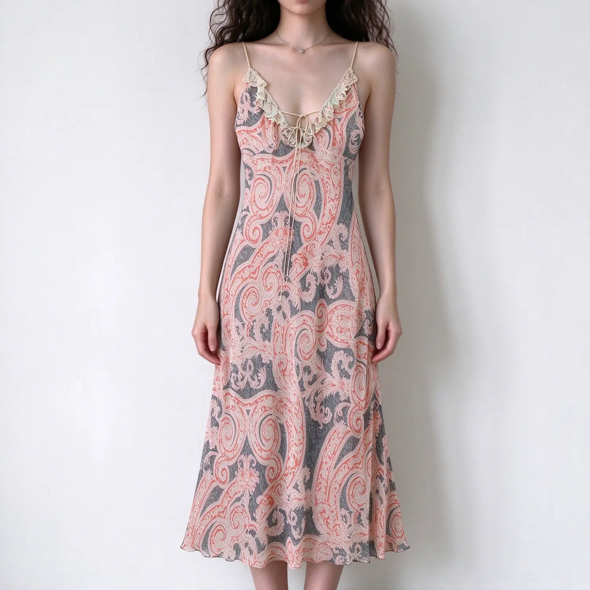 Model wearing pink grey paisley spaghetti strap maxi dress with lace ruffle trim and tie bust detail, white background