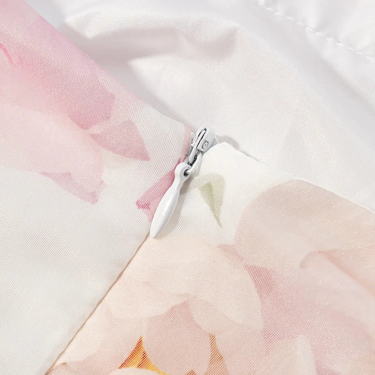 Close-up detail shot of the hidden side zipper on a pink peony floral halter dress, showing the white zipper pull and fabric.