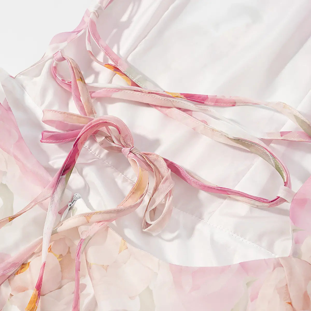 Close-up detail shot of the crisscross lace-up back on a pink peony floral halter dress, showing the fabric ties and zipper.