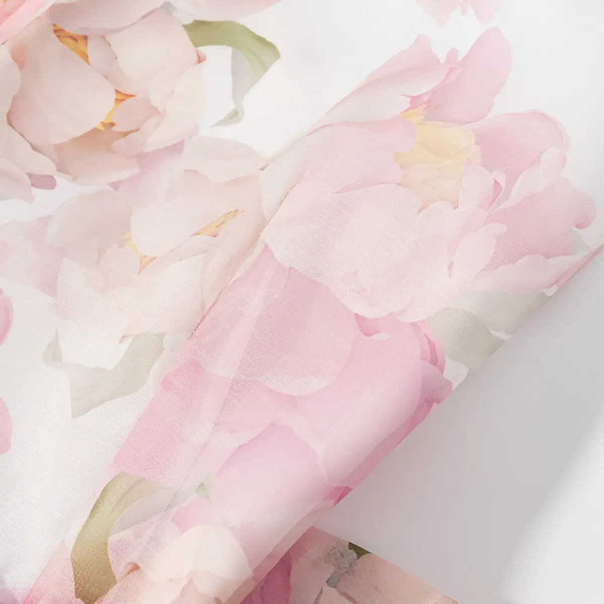 Close-up detail shot of the fabric on a pink peony floral halter dress, showing the watercolor-style print and sheer texture.
