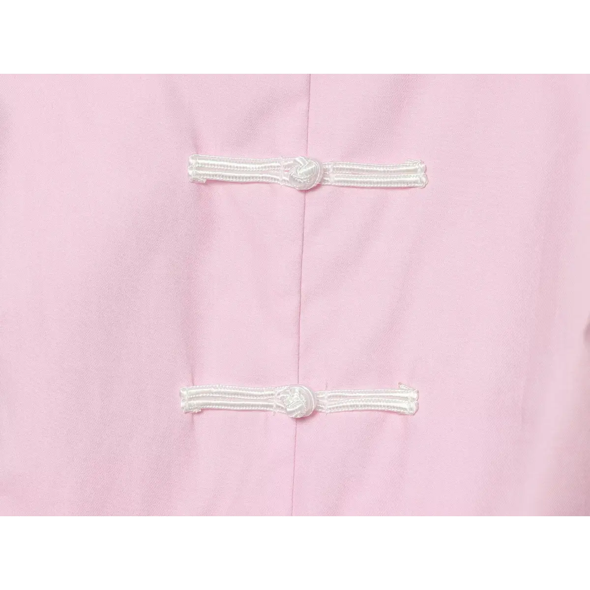 Close-up of the top's white traditional Chinese frog closures on light pink fabric.