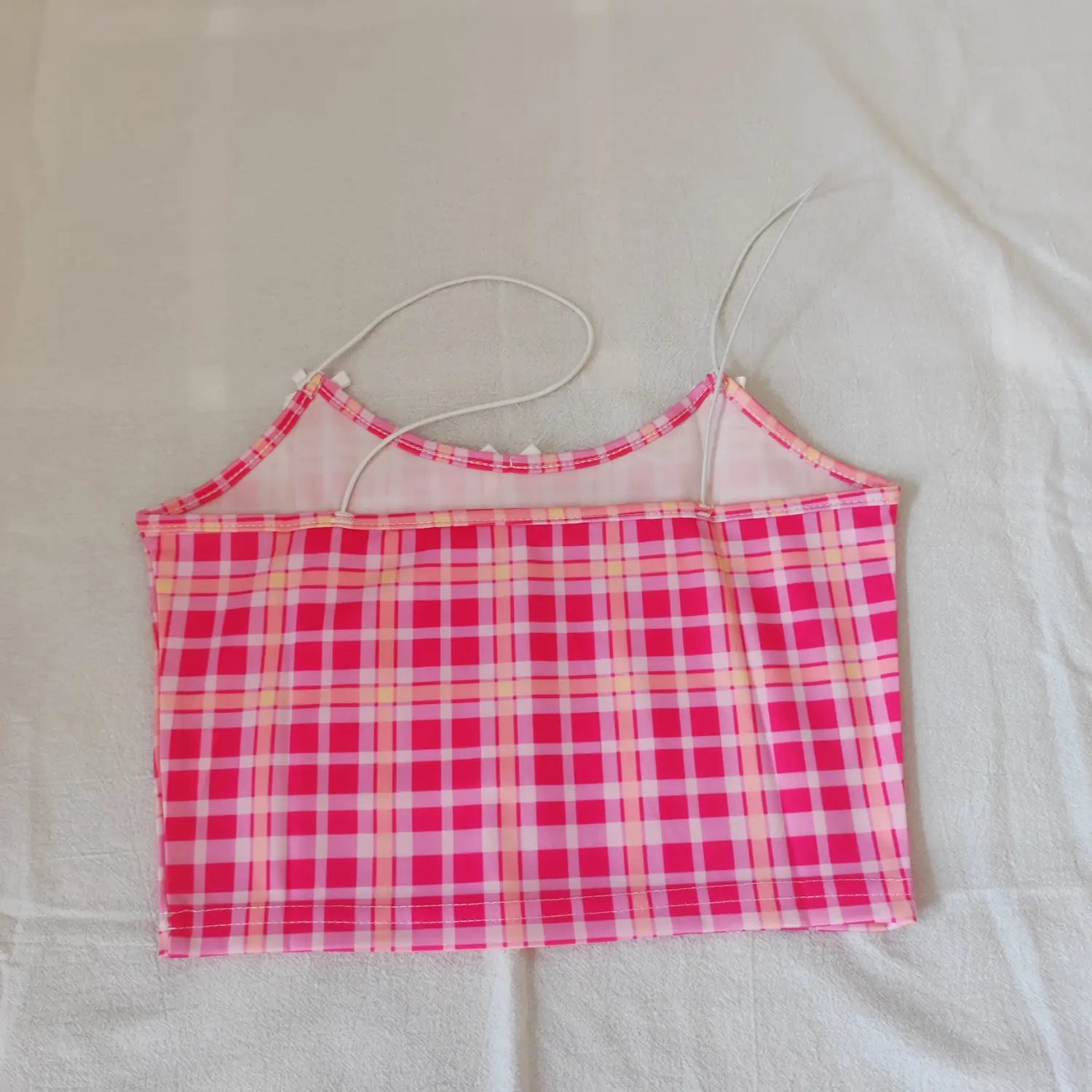 Flat lay back view pink plaid cropped cami top with thin white spaghetti straps