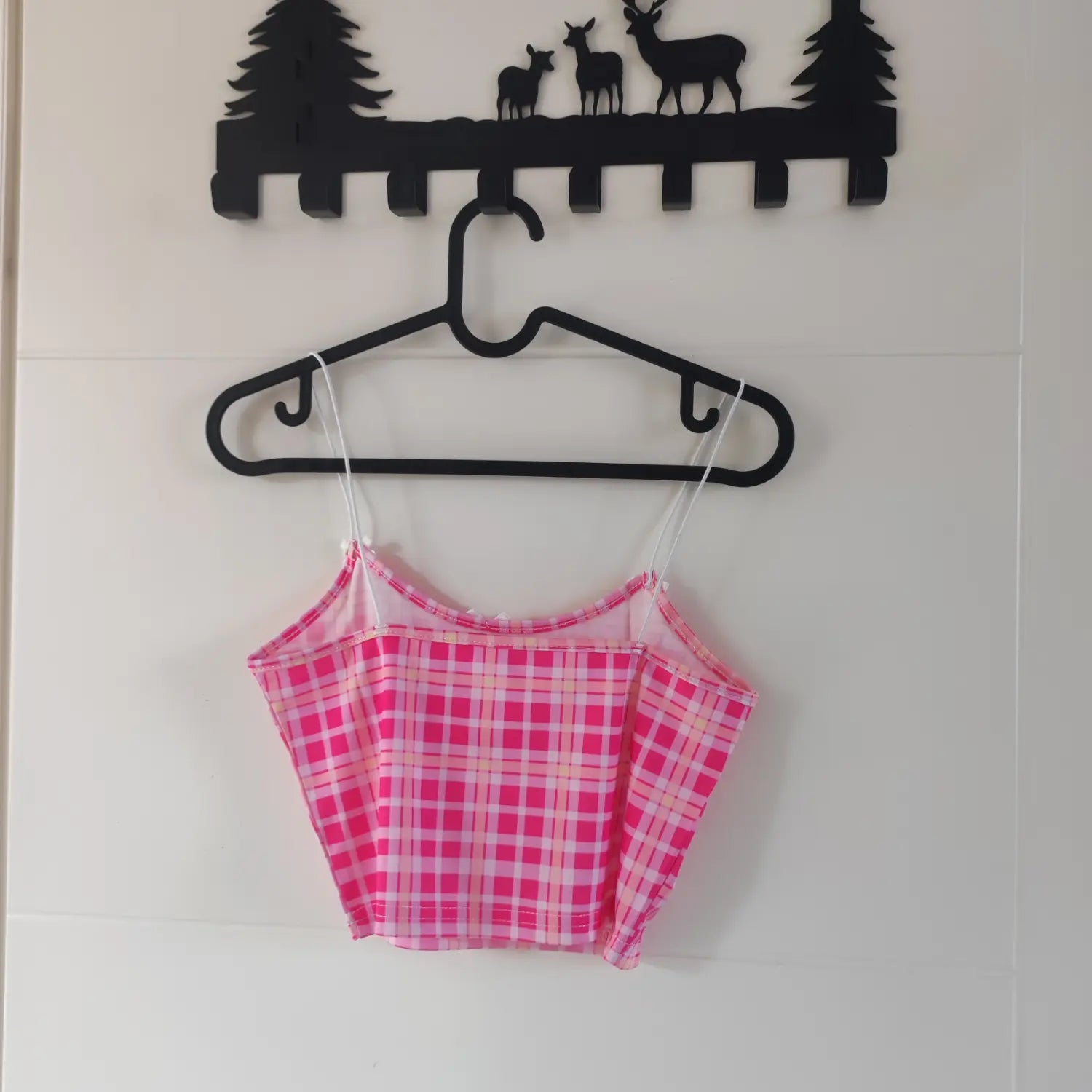 Hanging back view pink plaid crop cami top on black plastic hanger