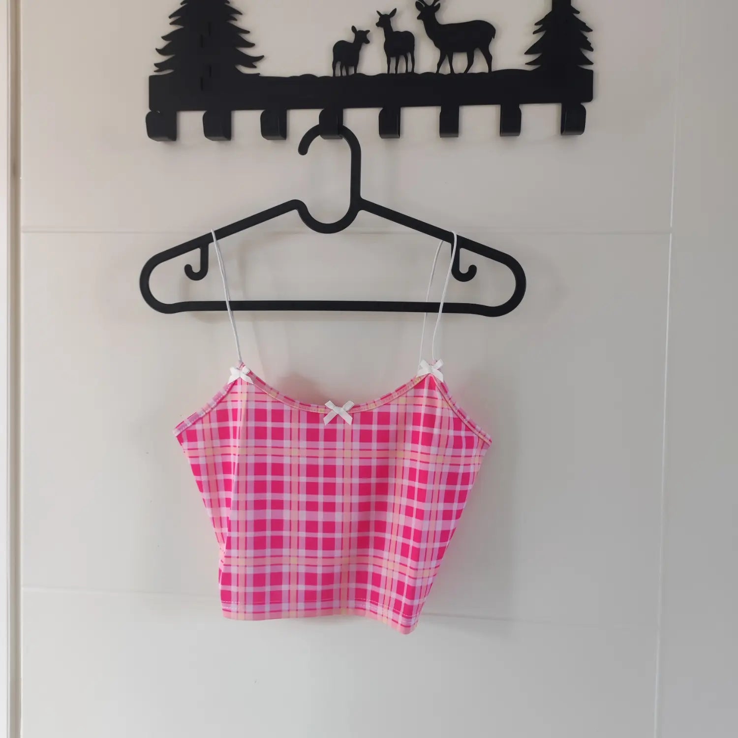 Hanging front view pink plaid cropped cami top with white bow decor on hanger